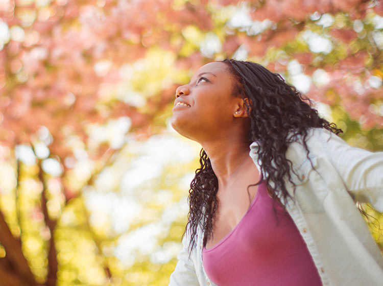 Woman looking up at colorful trees