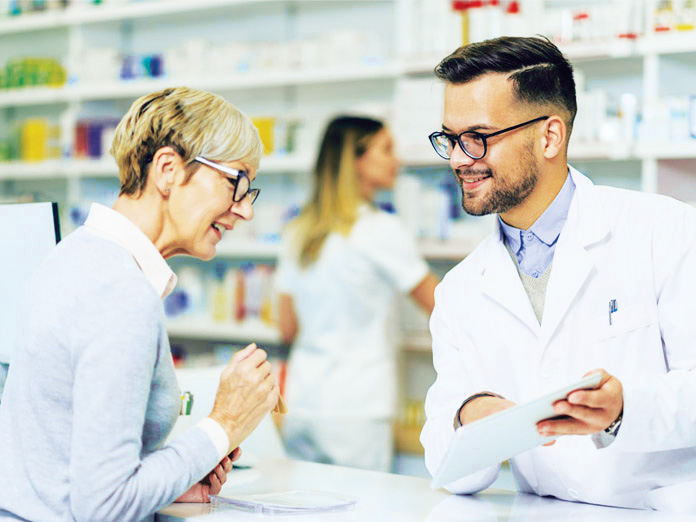 Imagen de un farmacéutico mostrándole a una mujer mayor qué medicamentos están incluidos en la cobertura de medicamentos con receta
